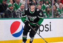 Action shot of a Dallas Stars hockey player in the neon black alternate uniform, illustrating the tough roster decisions facing management regarding Tyler Myers and the salary cap.