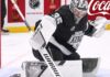 Los Angeles Kings goalie Darcy Kuemper in his black Kings jersey with number 35, making a stick save on the ice. This image relates to current NHL trade rumors concerning Kuemper's future with LA.