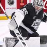 Los Angeles Kings Trade Rumors: Will Darcy Kuemper Be Moved? Los Angeles Kings goalie Darcy Kuemper in his black Kings jersey with number 35, making a stick save on the ice. This image relates to current NHL trade rumors concerning Kuemper's future with LA.