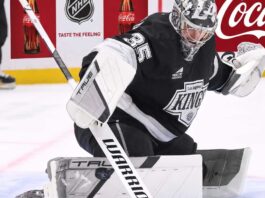 Los Angeles Kings Trade Rumors: Will Darcy Kuemper Be Moved? Los Angeles Kings goalie Darcy Kuemper in his black Kings jersey with number 35, making a stick save on the ice. This image relates to current NHL trade rumors concerning Kuemper's future with LA.