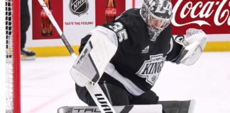 Los Angeles Kings Trade Rumors: Will Darcy Kuemper Be Moved? Los Angeles Kings goalie Darcy Kuemper in his black Kings jersey with number 35, making a stick save on the ice. This image relates to current NHL trade rumors concerning Kuemper's future with LA.