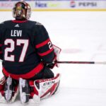 Ottawa Senators Trade Rumors: Devon Levi from Buffalo Sabres A conceptual visualization of goalie Devon Levi wearing an Ottawa Senators black home uniform with number 27, kneeling on the ice amidst NHL trade rumors linking the netminder to Ottawa.