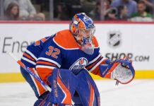 A conceptual photograph visualizing goaltender Filip Gustavsson wearing a royal blue and orange Edmonton Oilers uniform with number 32, representing the rumored NHL trade from the Minnesota Wild.