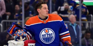 Photo-realistic mockup of Jordan Binnington wearing an Edmonton Oilers uniform and holding an Oilers-themed goalie mask, illustrating NHL trade rumors between the St. Louis Blues and Edmonton.