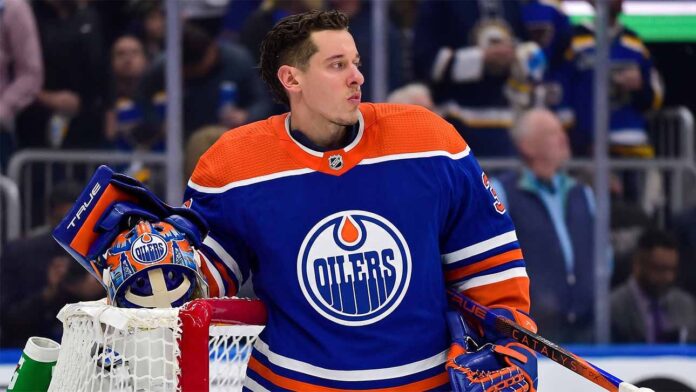 Photo-realistic mockup of Jordan Binnington wearing an Edmonton Oilers uniform and holding an Oilers-themed goalie mask, illustrating NHL trade rumors between the St. Louis Blues and Edmonton.