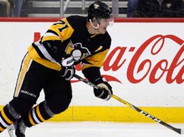 Pittsburgh Penguins center Evgeni Malkin (#71) in black and gold jersey, skating with his hockey stick along the arena boards featuring a prominent Coca-Cola advertisement.