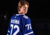 A visualization of top NHL prospect Gavin McKenna in a blue Toronto Maple Leafs jersey with 'MCKENNA' and number 72 on the back, looking over his shoulder in a dramatically lit hockey arena. Keywords: Toronto Maple Leafs, Gavin McKenna, NHL Draft.