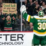 Minnesota Wild Trade Rumors: Will Jesper Wallstedt Be Moved? A photo of Minnesota Wild goaltender Jesper Wallstedt (30) in his green and gold alternate jersey celebrating on the ice as a fan in the stands holds a sign that reads 'Good luck on your new team Jesper!' during an NHL game, highlighting potential trade rumors.