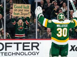 Minnesota Wild Trade Rumors: Will Jesper Wallstedt Be Moved? A photo of Minnesota Wild goaltender Jesper Wallstedt (30) in his green and gold alternate jersey celebrating on the ice as a fan in the stands holds a sign that reads 'Good luck on your new team Jesper!' during an NHL game, highlighting potential trade rumors.