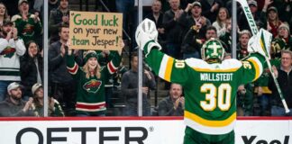 Minnesota Wild Trade Rumors: Will Jesper Wallstedt Be Moved? A photo of Minnesota Wild goaltender Jesper Wallstedt (30) in his green and gold alternate jersey celebrating on the ice as a fan in the stands holds a sign that reads 'Good luck on your new team Jesper!' during an NHL game, highlighting potential trade rumors.