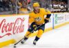 Nashville Predators forward Jonathan Marchessault skating with the puck in a yellow Predators jersey during an NHL game.