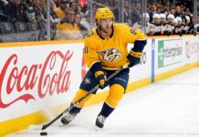 Nashville Predators forward Jonathan Marchessault skating with the puck in a yellow Predators jersey during an NHL game.