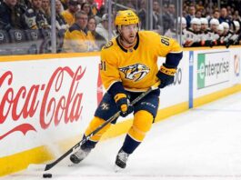 Nashville Predators forward Jonathan Marchessault skating with the puck in a yellow Predators jersey during an NHL game.