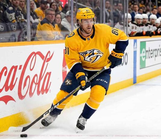 Nashville Predators forward Jonathan Marchessault skating with the puck in a yellow Predators jersey during an NHL game.