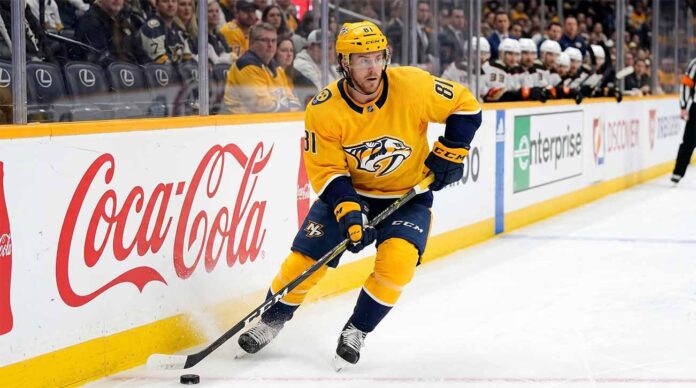 Nashville Predators forward Jonathan Marchessault skating with the puck in a yellow Predators jersey during an NHL game.