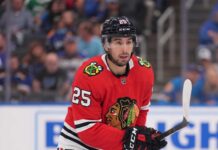 NHL player Jordan Kyrou wearing a Chicago Blackhawks red jersey and helmet on the ice, visualizing trade rumors connecting him to Chicago.