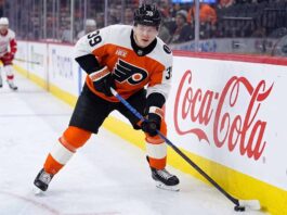 Philadelphia Flyers Matvei Michkov Trade Rumors: Will He Be Dealt? Philadelphia Flyers forward Matvei Michkov in action on the ice, stickhandling near the boards featuring a large Coca-Cola advertisement during an NHL game.