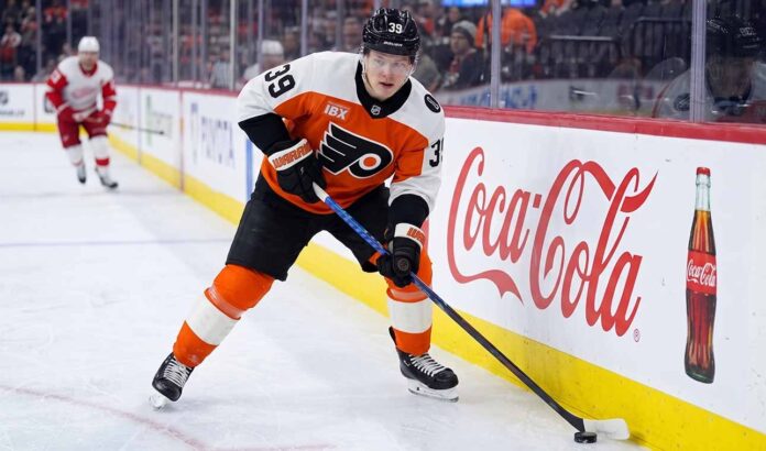 Philadelphia Flyers forward Matvei Michkov in action on the ice, stickhandling near the boards featuring a large Coca-Cola advertisement during an NHL game.