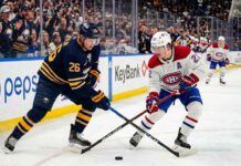 Montreal Canadiens Cole Caufield battles Buffalo Sabres Rasmus Dahlin for a loose puck during 2026 NHL Playoffs action at KeyBank Center.