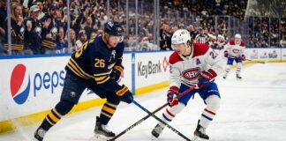 Montreal Canadiens Cole Caufield battles Buffalo Sabres Rasmus Dahlin for a loose puck during 2026 NHL Playoffs action at KeyBank Center.