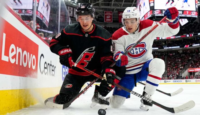 montreal-canadiens-carolina-hurricanes-game-1-2026 Montreal Canadiens and Carolina Hurricanes players in a fierce board battle during Game 1 of the 2026 NHL Eastern Conference Finals.
