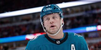 A conceptual image of long-time Toronto Maple Leafs defenseman Morgan Rielly wearing a teal San Jose Sharks home uniform and helmet, visualizing recent NHL trade rumors.