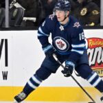 Winnipeg Jets Offer Sheet Rumors: Targeting Pavel Dorofeyev A close-up action shot on ice of hockey player Pavel Dorofeyev, featuring his likeness and low-crouched pose, now in a navy blue Winnipeg Jets home uniform and helmet with number 16, controlling a puck with his stick and creating ice spray.