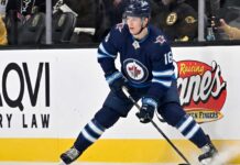 Winnipeg Jets Offer Sheet Rumors: Targeting Pavel Dorofeyev A close-up action shot on ice of hockey player Pavel Dorofeyev, featuring his likeness and low-crouched pose, now in a navy blue Winnipeg Jets home uniform and helmet with number 16, controlling a puck with his stick and creating ice spray.