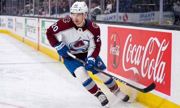ross-colton-colorado-avalanche-trade-rumors A photorealistic image of NHL forward Ross Colton, wearing his Colorado Avalanche away jersey (number 20 on sleeves and helmet), in an aggressive skating stride along the ice hockey boards. A large, prominent Coca-Cola advertising panel is clearly visible on the boards to his right.