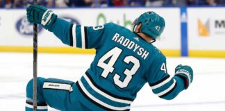 San Jose Sharks free agency target defenseman Darren Raddysh celebrating a goal in a conceptual teal home uniform on the ice with his stick raised.