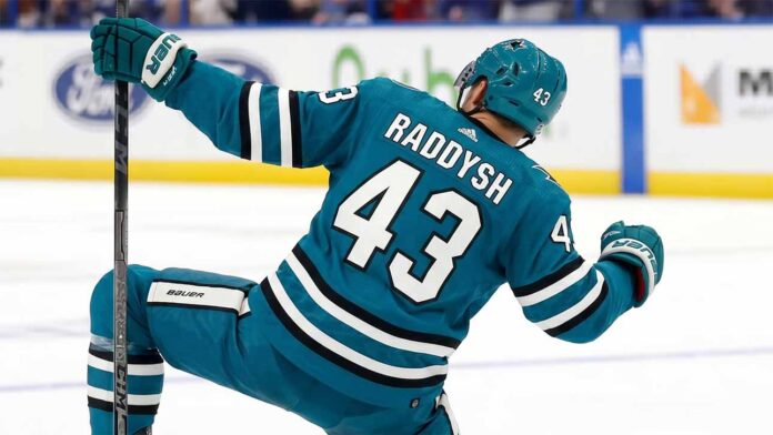 San Jose Sharks free agency target defenseman Darren Raddysh celebrating a goal in a conceptual teal home uniform on the ice with his stick raised.