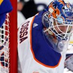NHL goaltender Sebastian Cossa pictured in fictional Edmonton Oilers uniform and custom orange and blue goalie mask, visualizing recent trade rumors.
