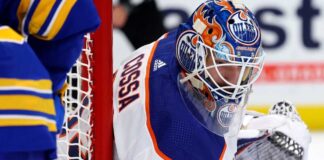 NHL goaltender Sebastian Cossa pictured in fictional Edmonton Oilers uniform and custom orange and blue goalie mask, visualizing recent trade rumors.