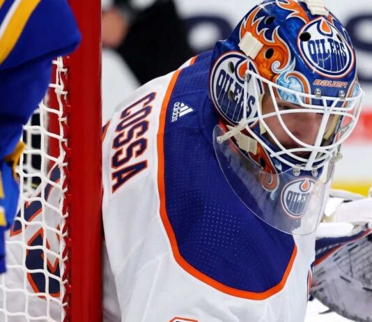 NHL goaltender Sebastian Cossa pictured in fictional Edmonton Oilers uniform and custom orange and blue goalie mask, visualizing recent trade rumors.