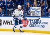 An emotional Tampa Bay Lightning fan holds a hand-made sign that reads 'Please don't leave Tampa Nikita!' during a hockey game, directed at forward Nikita Kucherov.