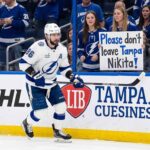 An emotional Tampa Bay Lightning fan holds a hand-made sign that reads 'Please don't leave Tampa Nikita!' during a hockey game, directed at forward Nikita Kucherov.