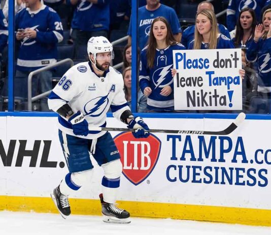 An emotional Tampa Bay Lightning fan holds a hand-made sign that reads 'Please don't leave Tampa Nikita!' during a hockey game, directed at forward Nikita Kucherov.