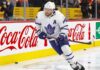 Toronto Maple Leafs defenseman Morgan Rielly (#44) skating with the puck during an NHL game, featuring Coca-Cola and Enterprise advertising on the arena boards.