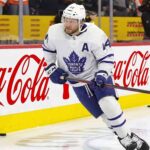 Toronto Maple Leafs Asking Morgan Rielly to Waive NMC? Toronto Maple Leafs defenseman Morgan Rielly (#44) skating with the puck during an NHL game, featuring Coca-Cola and Enterprise advertising on the arena boards.