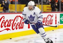 Toronto Maple Leafs Asking Morgan Rielly to Waive NMC? Toronto Maple Leafs defenseman Morgan Rielly (#44) skating with the puck during an NHL game, featuring Coca-Cola and Enterprise advertising on the arena boards.
