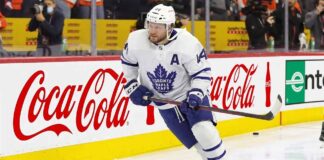 Toronto Maple Leafs defenseman Morgan Rielly (#44) skating with the puck during an NHL game, featuring Coca-Cola and Enterprise advertising on the arena boards.