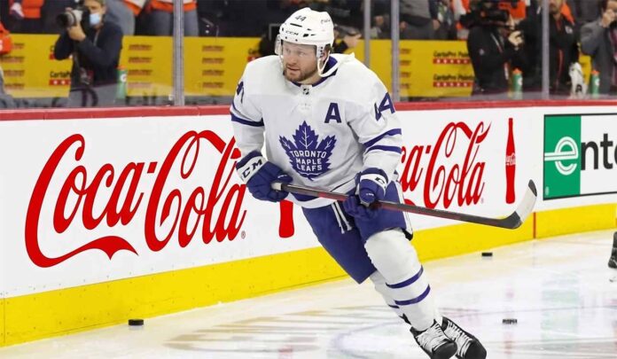 toronto-maple-leafs-morgan-rielly-trade-rumors Toronto Maple Leafs defenseman Morgan Rielly (#44) skating with the puck during an NHL game, featuring Coca-Cola and Enterprise advertising on the arena boards.