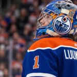 Edmonton Oilers Trade Rumors: Ukka-Pekka Luukkonen Sabres Deal A close-up profile view of Buffalo Sabres goaltender Ukko-Pekka Luukkonen, wearing his custom-painted goalie mask and blue jersey with 'LUUKKONEN' visible on the back. This image is used in an analysis of a potential trade linking him to the Edmonton Oilers.