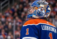 A close-up profile view of Buffalo Sabres goaltender Ukko-Pekka Luukkonen, wearing his custom-painted goalie mask and blue jersey with 'LUUKKONEN' visible on the back. This image is used in an analysis of a potential trade linking him to the Edmonton Oilers.