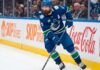 Vancouver Canucks defenseman Filip Hronek skating with the puck looking for a passing lane during an NHL game at Rogers Arena.