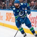 Vancouver Canucks defenseman Filip Hronek skating with the puck looking for a passing lane during an NHL game at Rogers Arena.