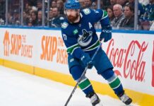 Vancouver Canucks defenseman Filip Hronek skating with the puck looking for a passing lane during an NHL game at Rogers Arena.