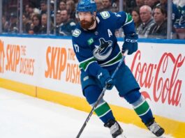 Vancouver Canucks defenseman Filip Hronek skating with the puck looking for a passing lane during an NHL game at Rogers Arena.