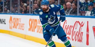 Vancouver Canucks defenseman Filip Hronek skating with the puck looking for a passing lane during an NHL game at Rogers Arena.