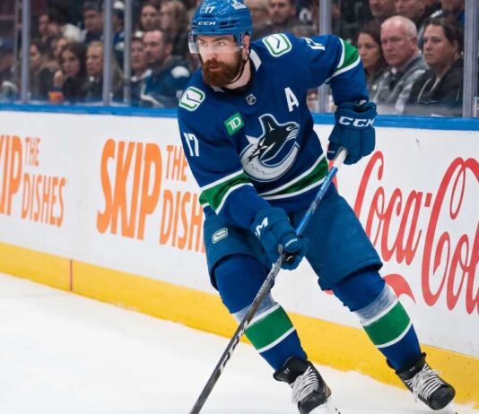 Vancouver Canucks defenseman Filip Hronek skating with the puck looking for a passing lane during an NHL game at Rogers Arena.